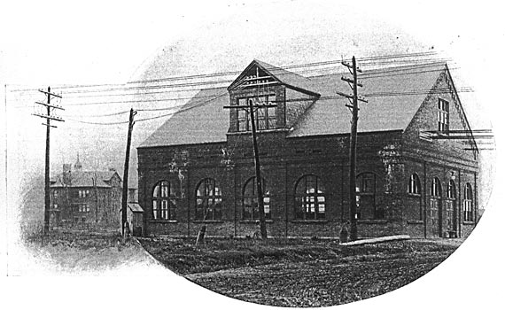 FIG. 1.  THE EXTERIOR OF THE TRANSFORMING STATION OF THE TONAWANDA POWER COMPANY/The six upper wires on the poles in the foreground are the two three-phase lines running from Niagara on the right toward Buffalo on the left. Taps from these pass into the left-hand side of the gable. The lower three wires passing out to the right form the 11,000-volt branch line to Lockport. The heavy wires passing out from the right-hand end of the building are the railway feeders, and the lighter wires beyond them are the central station lines.