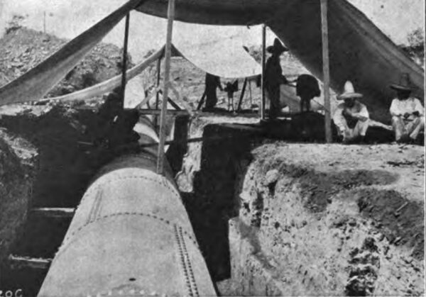 PHOTOGRAPH NO. 21. BOILERMAKERS AT WORK IN THE FIELD, RIVETING UP THE PIPE