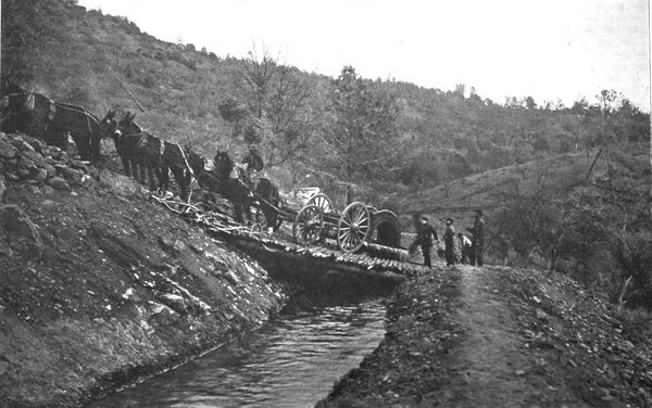 HAULING A SECTION OF AN ARMATURE TO THE POWER HOUSE. THE UP-HILL WORK IS NOT EASY