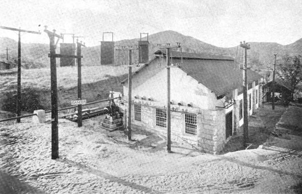 Fig. 13 Exterior Present No. 1 Power House, Showing Incoming No. 3 Line on the Right, Choke Coils on Poles and Lightning Arrester Sheds on the Left