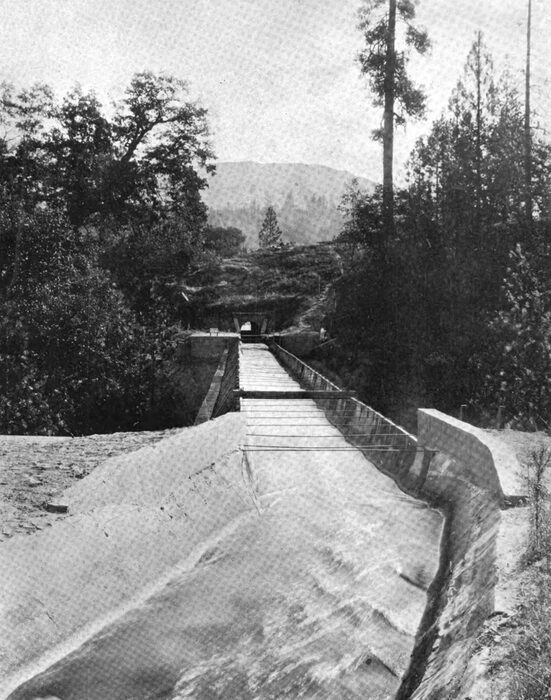 Fig. 5 Ditch, Flume and Tunnel, No. 3 Conduit Line. Down the Canyon from the Crane Valley dam, beneath the smoky veil in the view in Fig. 2, the conduit extends for 4.22 miles, a part of which is 5 feet wide at the bottom, the remainder being 6 feet in width. The ditch thus formed is in a substantial bed of disintegrated granite the greater part of its length and is plastered with cement."