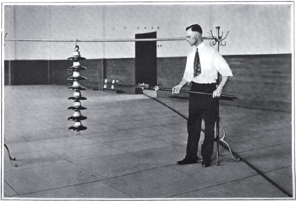 METHOD OF APPLYING TEST FORK TO INSULATOR STRING IN TESTING OUT INDIVIDUAL UNITS. Fork weighs 14 pounds complete and is easily handled on tower.