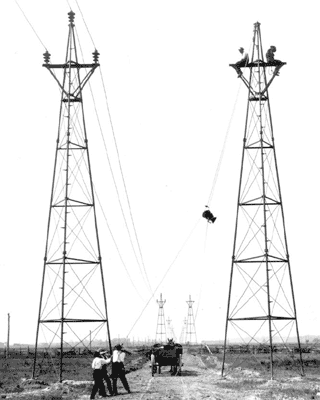 GOOD OLD DAYS? Linemen use muscle power to hoist insulators atop "windmill" towers, an innovation over wood pole structures for higher voltages.  Line was probably in western NY.  Note horsedrawn "line truck"